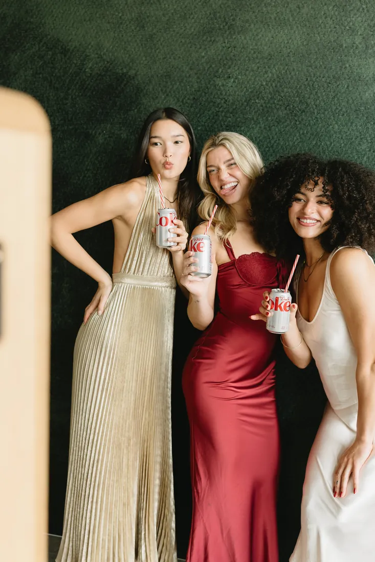 Friends with drinks posing in front of the booth backdrop